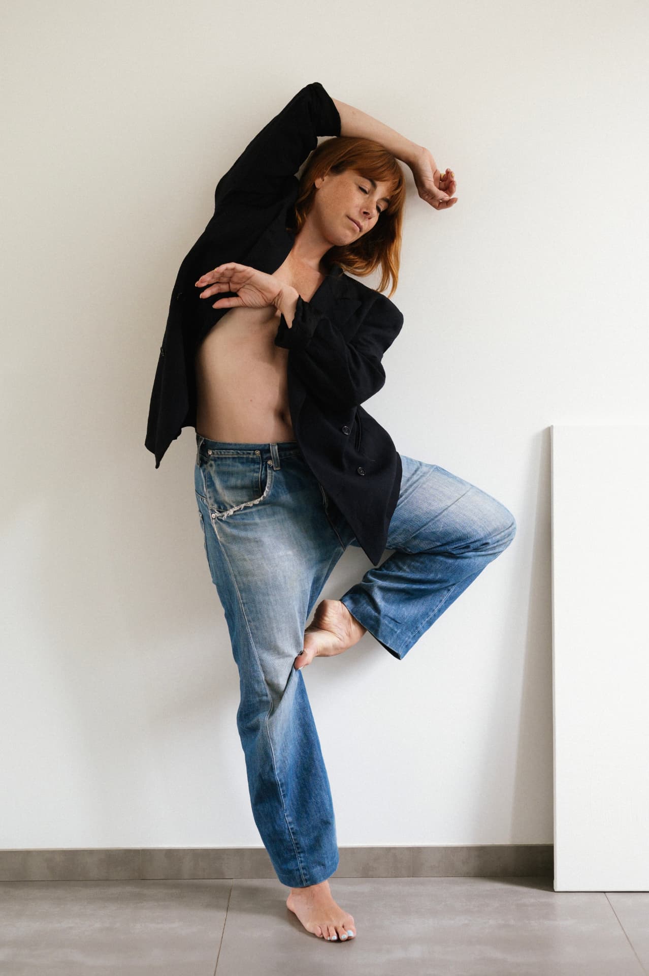 Équilibre pieds nus, veste noire et jean